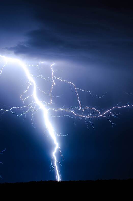 A bolt of lightning against a dark-blue sky.